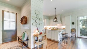 A spacious kitchen with white cabinets, a wooden floor, and a hanging light fixture. - Designer Cashiers Cottage, Perfect Porch, EV Plug (Cashiers)