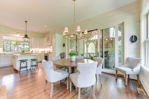 A spacious kitchen with a central island, wooden flooring, and a chandelier.