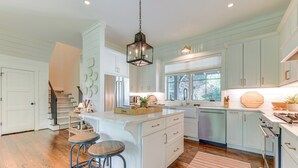 A spacious kitchen with a large island, wooden flooring, and a view of the outdoors. - Designer Cashiers Cottage, Perfect Porch, EV Plug (Cashiers)