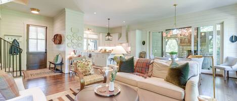 A spacious living room with a large sofa, a coffee table, and a dining area with a kitchen in the background.