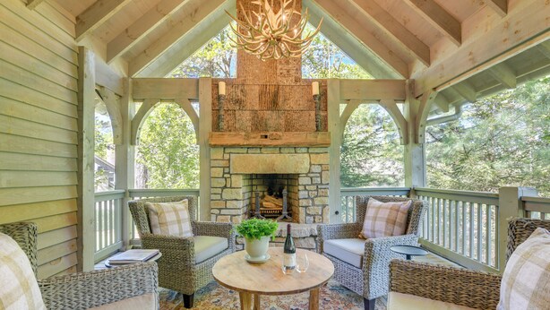 A covered porch with wicker furniture, a stone fireplace, and a chandelier. - Designer Cashiers Cottage, Perfect Porch, EV Plug (Cashiers)