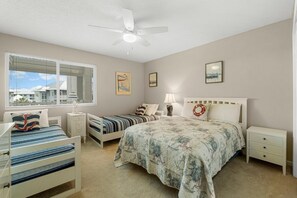 A bedroom with a large bed, two smaller beds, a ceiling fan, and a window with blinds. - New to Rental Market, Beachfront, Two Beach Service Chairs included! (Santa Rosa)