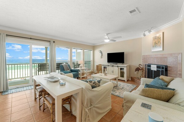 A spacious living area with a balcony, a flat-screen TV, and a fireplace. - New to Rental Market, Beachfront, Two Beach Service Chairs included! (Santa Rosa)