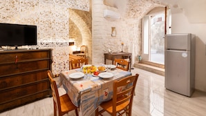 A dining area with a stone wall, wooden furniture, and a modern refrigerator. - 3929 Casa Ferrante by Barbarhouse (Vieste)