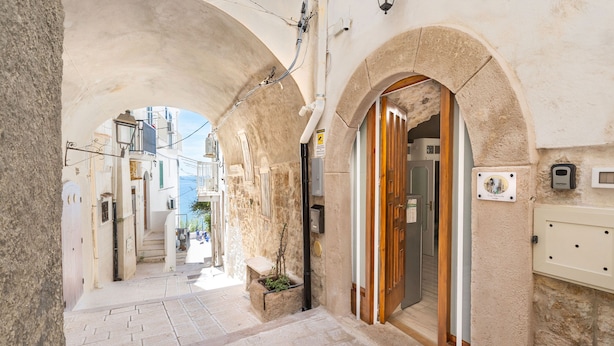 A narrow street with stone buildings, a wooden door, and a small planter with plants. - 3929 Casa Ferrante by Barbarhouse (Vieste)