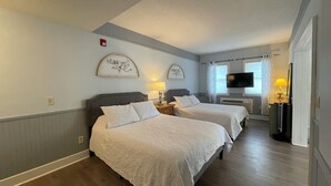 Une chambre d’hôtel avec deux lits, une télévision et une fenêtre avec des rideaux.