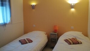 Una habitación con dos camas individuales, cada una con una almohada y una mesita de noche con lámpara.