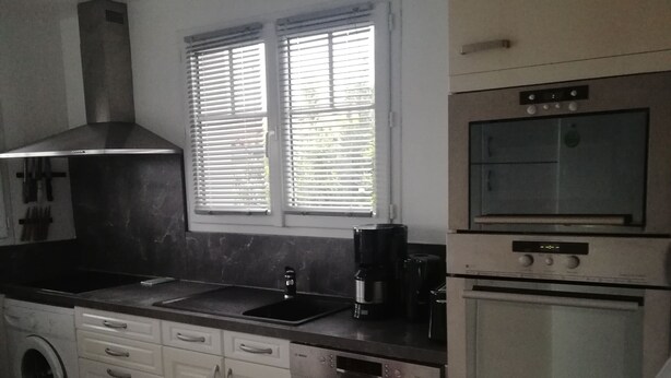 Una cocina compacta equipada con lavadora, cafetera y microondas.