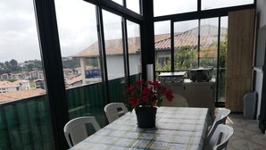 Un balcón con mesa y sillas, una planta en maceta y vistas a edificios y zonas verdes.