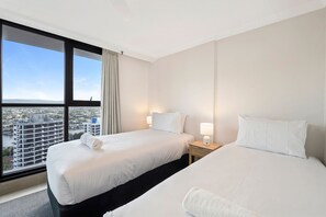 Una habitación de hotel con dos camas, un ventanal grande y vista a la ciudad.