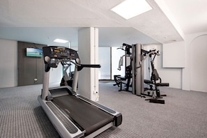 Ett gym med löpband, styrketräningsmaskiner och en tv-skärm.