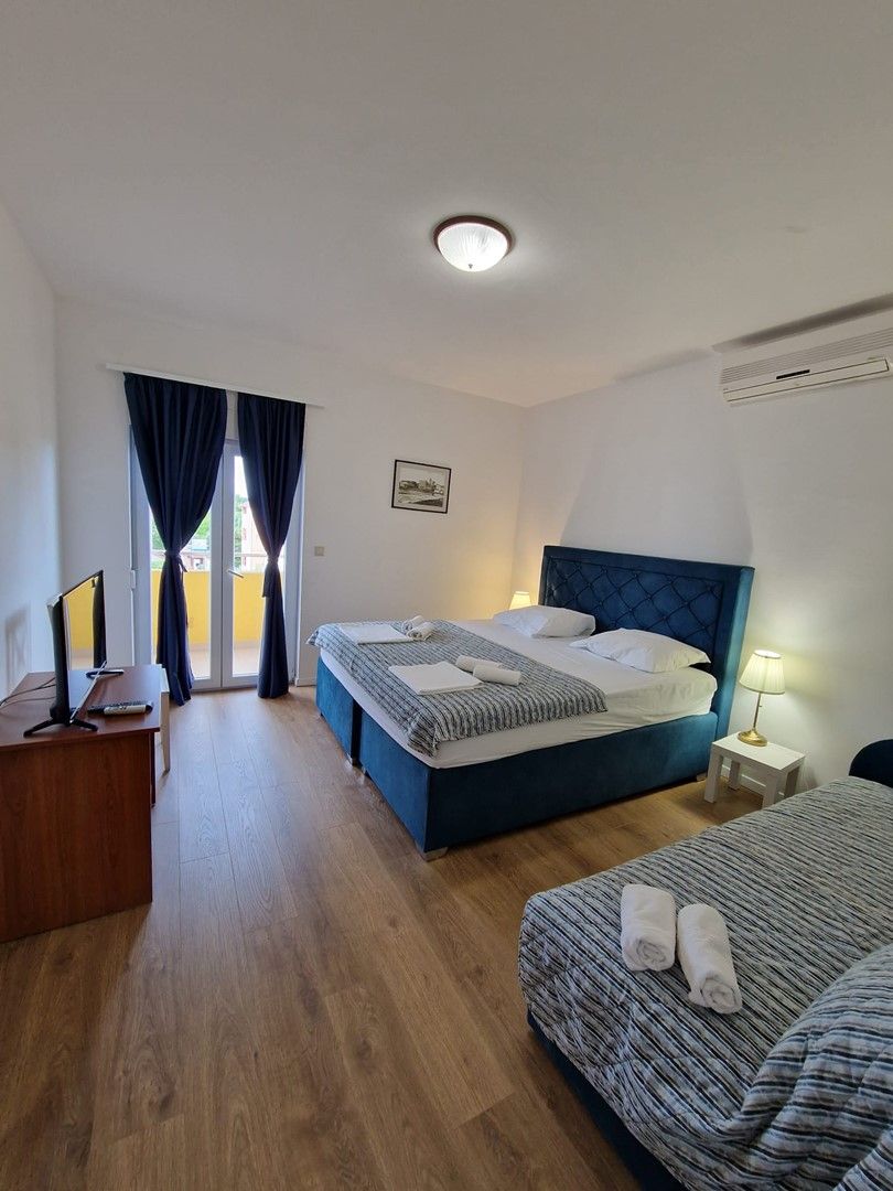 Una camera d'albergo con un letto, una scrivania, una sedia, una lampada e una finestra con tende.