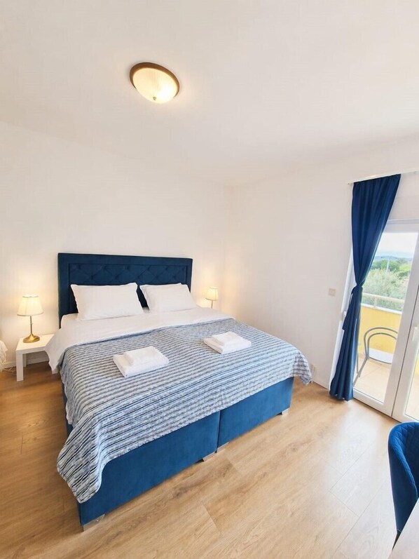 Une chambre d’hôtel avec un lit, deux lampes de chevet, une vue par la fenêtre, qui est dotée de rideaux, et un balcon.
