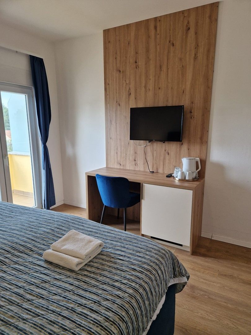 Una camera d'albergo con un letto, una scrivania con una sedia, una televisione e una macchina per il caffè.