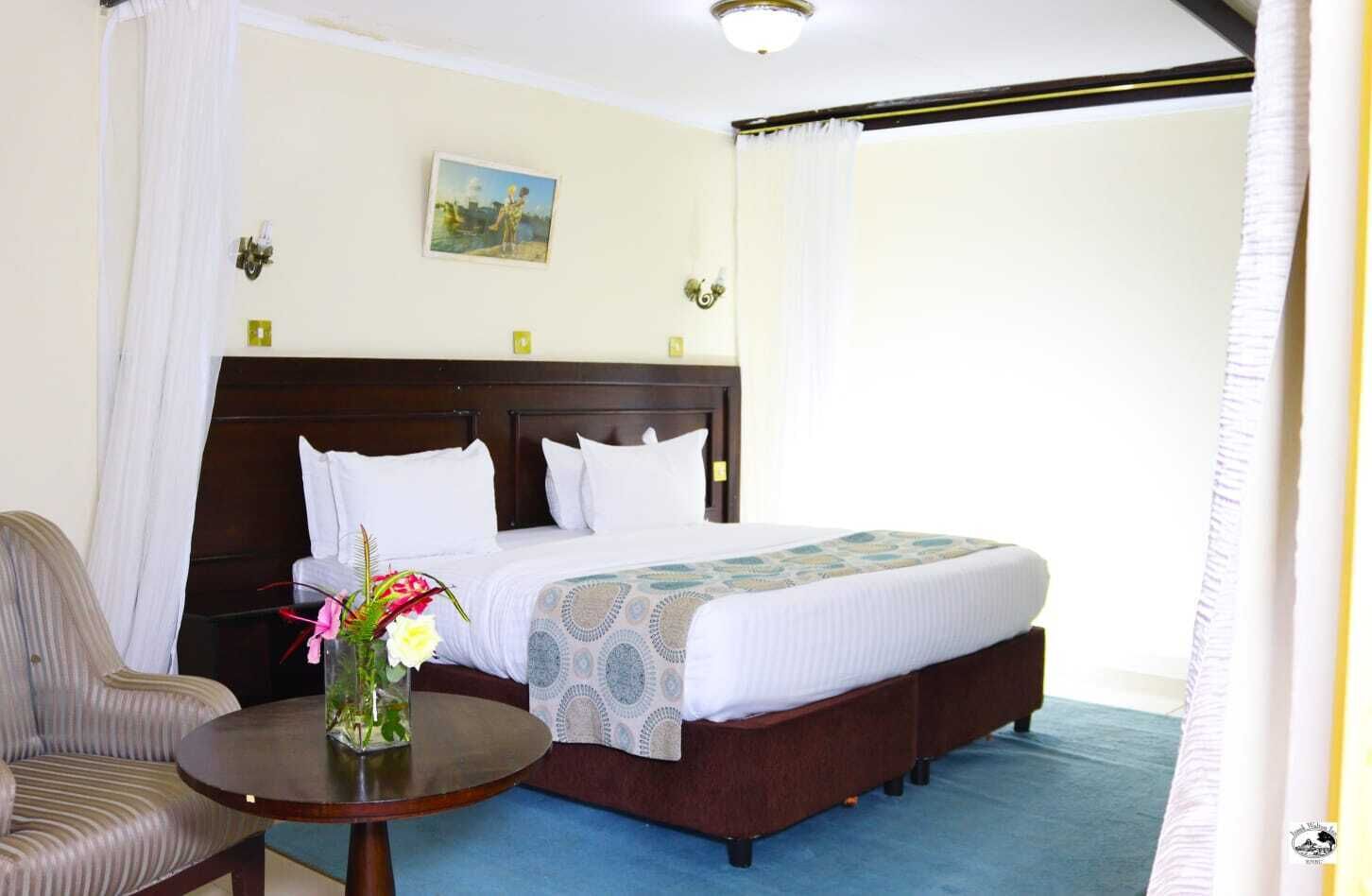 A hotel room with a bed, a chair, and a small table with a vase of flowers.