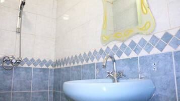 A bathroom with a blue sink, a shower, and a mirror with a yellow frame.