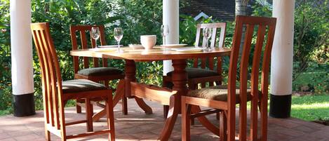 A wooden table with chairs, surrounded by greenery.