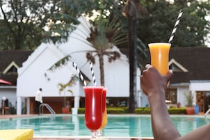 Dos bebidas con pajitas frente a una piscina.