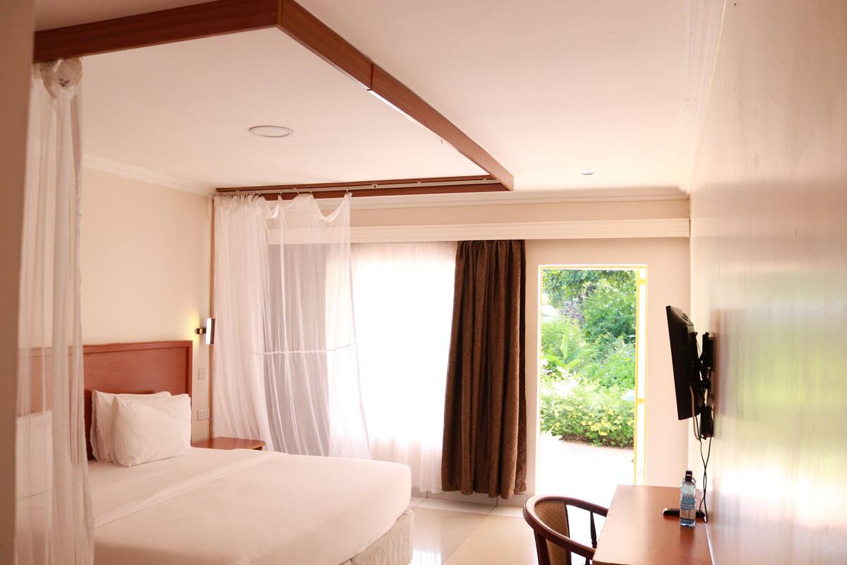 Una habitación de hotel con cama, escritorio y televisor montado en la pared.