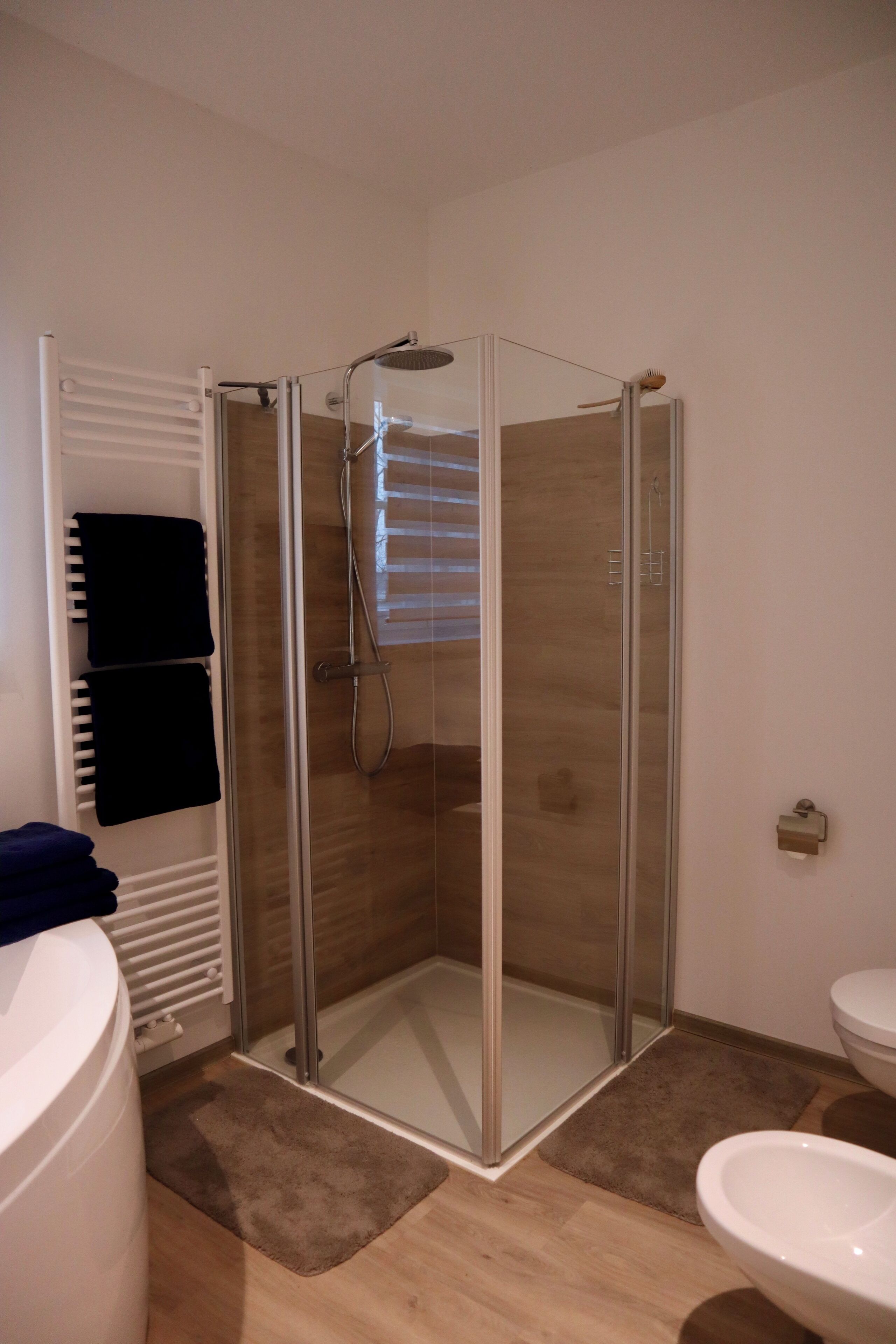 Un baño moderno con ducha envuelta en vidrio, inodoro blanco y lavamanos blanco.