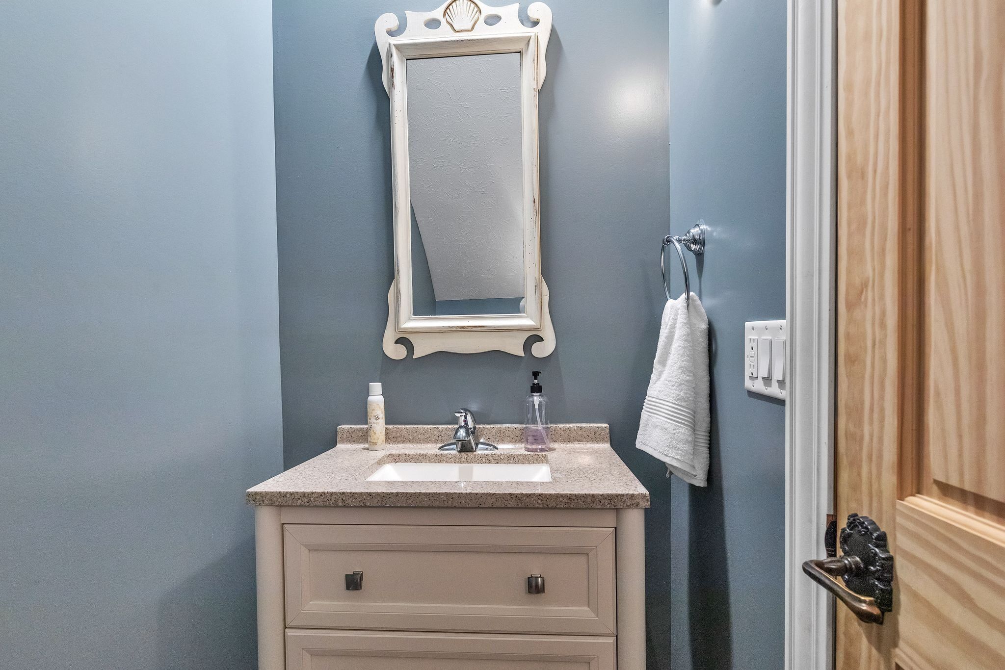 A bathroom with a sink, mirror, and towel rack.