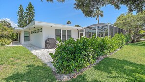 A modern house with a covered patio, a barbecue grill, and a well-maintained garden. - The Windward House 3 Bedroom Home by RedAwning (Siesta Key)