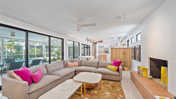A modern living room with a sectional sofa, a coffee table, and a fireplace. - The Windward House 3 Bedroom Home by RedAwning (Siesta Key)