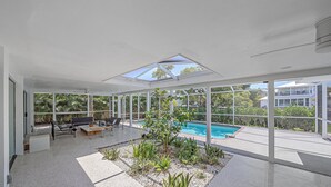 Un patio moderno al aire libre con piscina, zona de estar y vistas a la vegetación circundante.