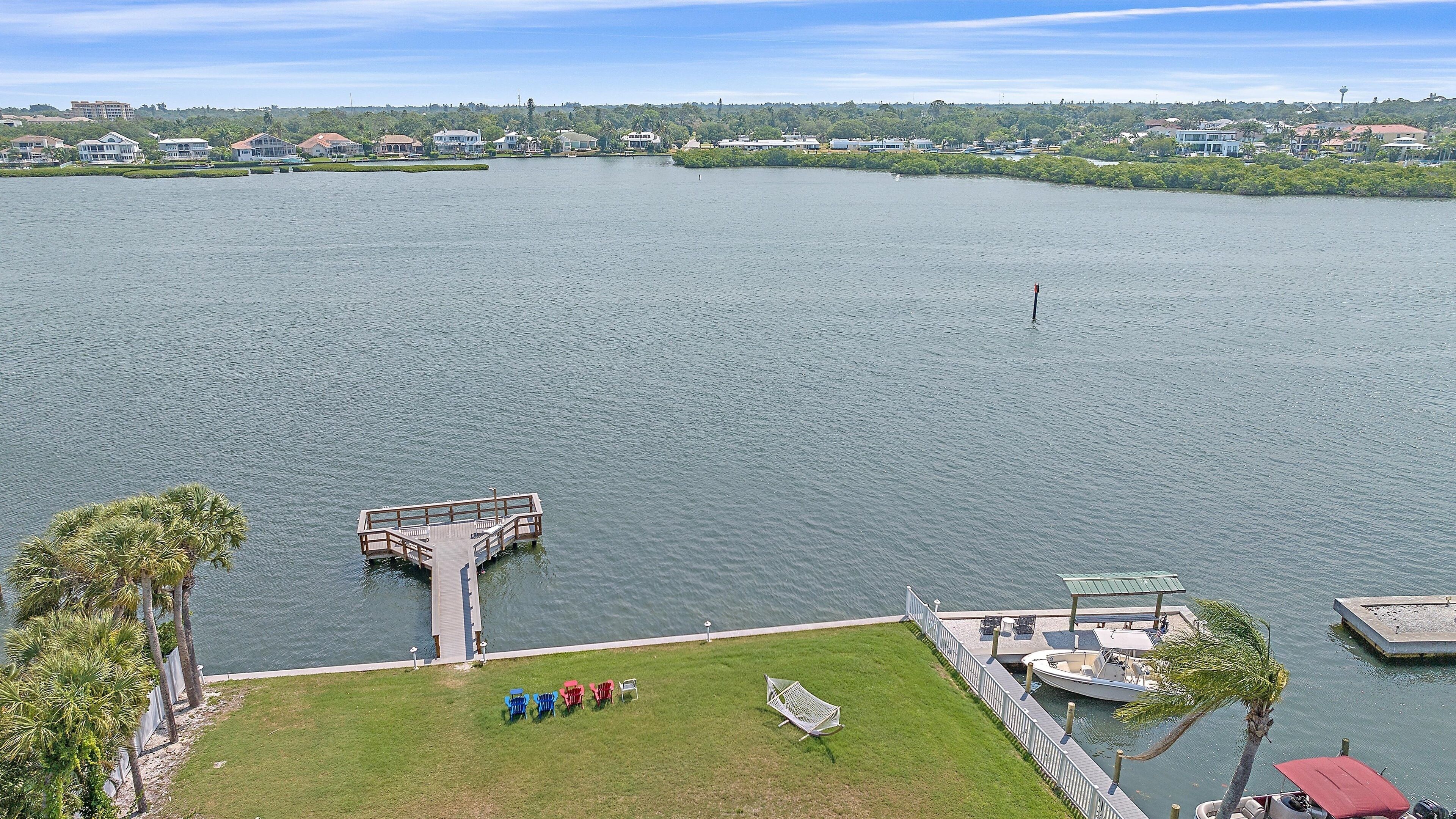 A waterfront property with a dock, grassy area, and a boat.