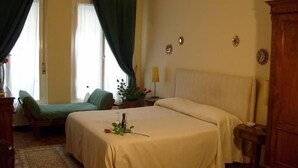 A bedroom with a bed, a chair, a nightstand, a lamp, and a window with curtains.