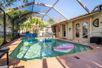 A heated pool, dining area, sun lounge chairs and hangout area