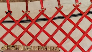 Un lit avec une couverture à motifs, une tête de lit et une structure en treillis rouge en arrière-plan.