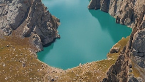 Un paysage montagneux avec un lac turquoise, entouré d’un terrain rocheux.