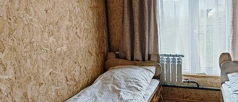 Une chambre avec deux lits superposés en bois, une fenêtre avec des rideaux et un radiateur.