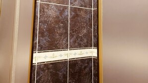 A bathroom with dark brown tiles and a decorative border. - Apartmens Sea House Dobra Voda (Dobre Vode)