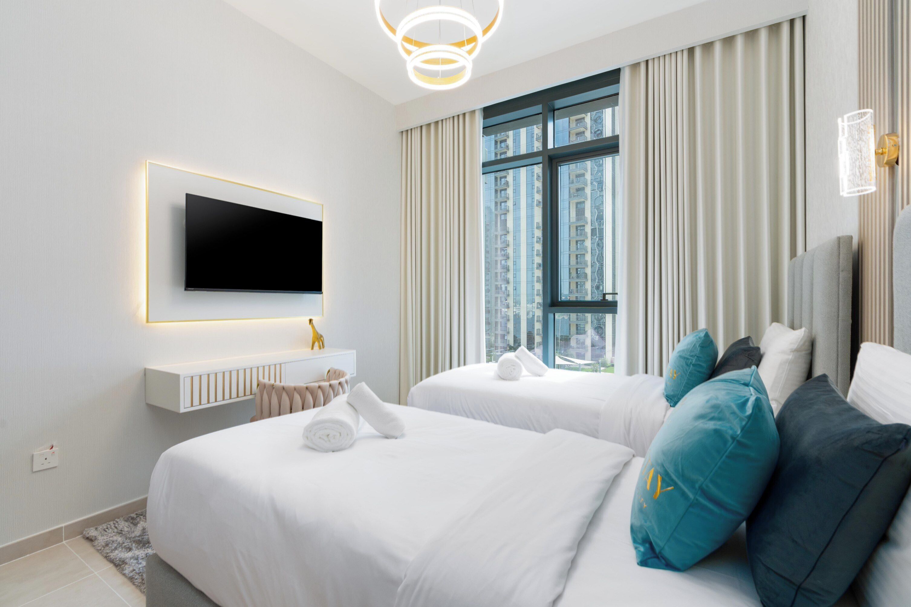 Una habitación de hotel moderna con dos camas, un televisor de pantalla plana, un ventanal grande con cortinas y una decoración minimalista.