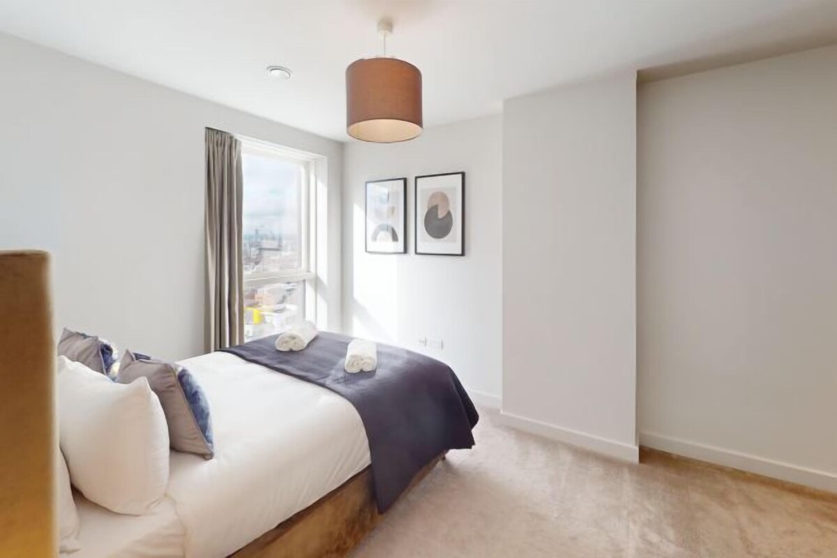 Une chambre à coucher avec un lit, une fenêtre et un luminaire suspendu.