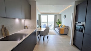 A modern kitchen with a dining area, a sofa, and a view of the city. - Charles Hope Manchester Centre (Manchester)