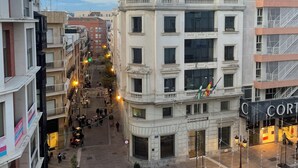 A plaza with a central monument, surrounding buildings, and a café. - Apartamento Centro muy Luminoso (Huelva)