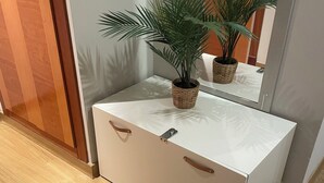 A compact room with a white chest of drawers, a small potted plant, and a mirror reflecting part of the room. - Apartamento Centro muy Luminoso (Huelva)