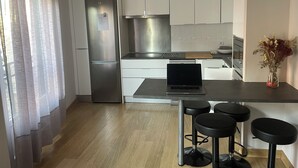 A modern kitchen with a built-in refrigerator, a laptop on the counter, and bar stools. - Apartamento Centro muy Luminoso (Huelva)