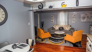 A modern living room with a sofa, two armchairs, a coffee table, and a dining area with a table and chairs. - Downtown Cozy 2 BR Apt - 4min drive MardiGras Park (Mobile)