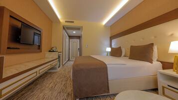 A hotel room with a bed, bedside table, TV, and a carpeted floor.