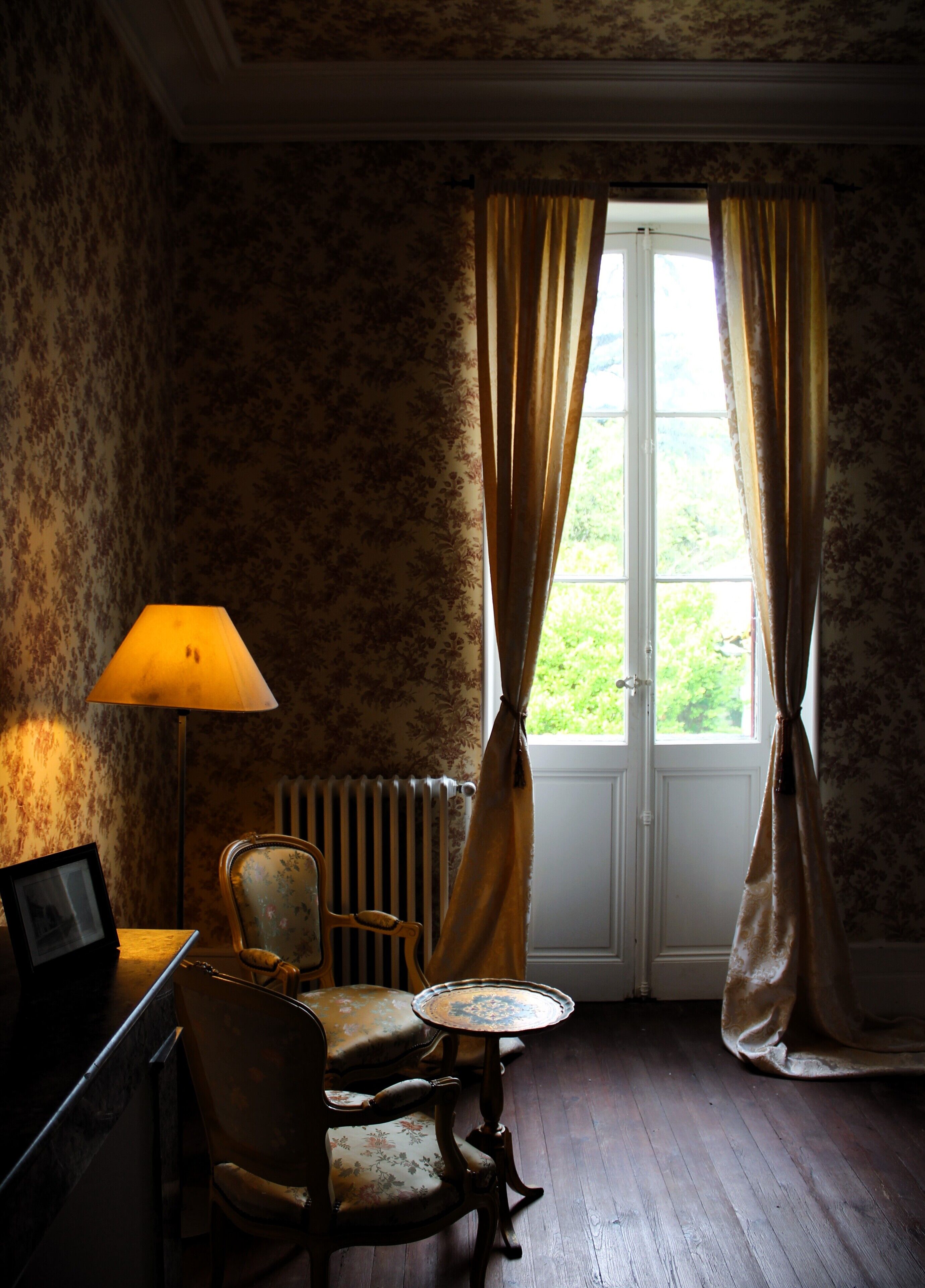 A room with a radiator, a chair, a table, and a lamp.