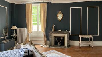 Une pièce comprenant un lit, une cheminée, un miroir et une fenêtre avec des rideaux.