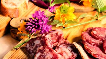 Une planche en bois garnie de tranches de salami, de pain et de fleurs.