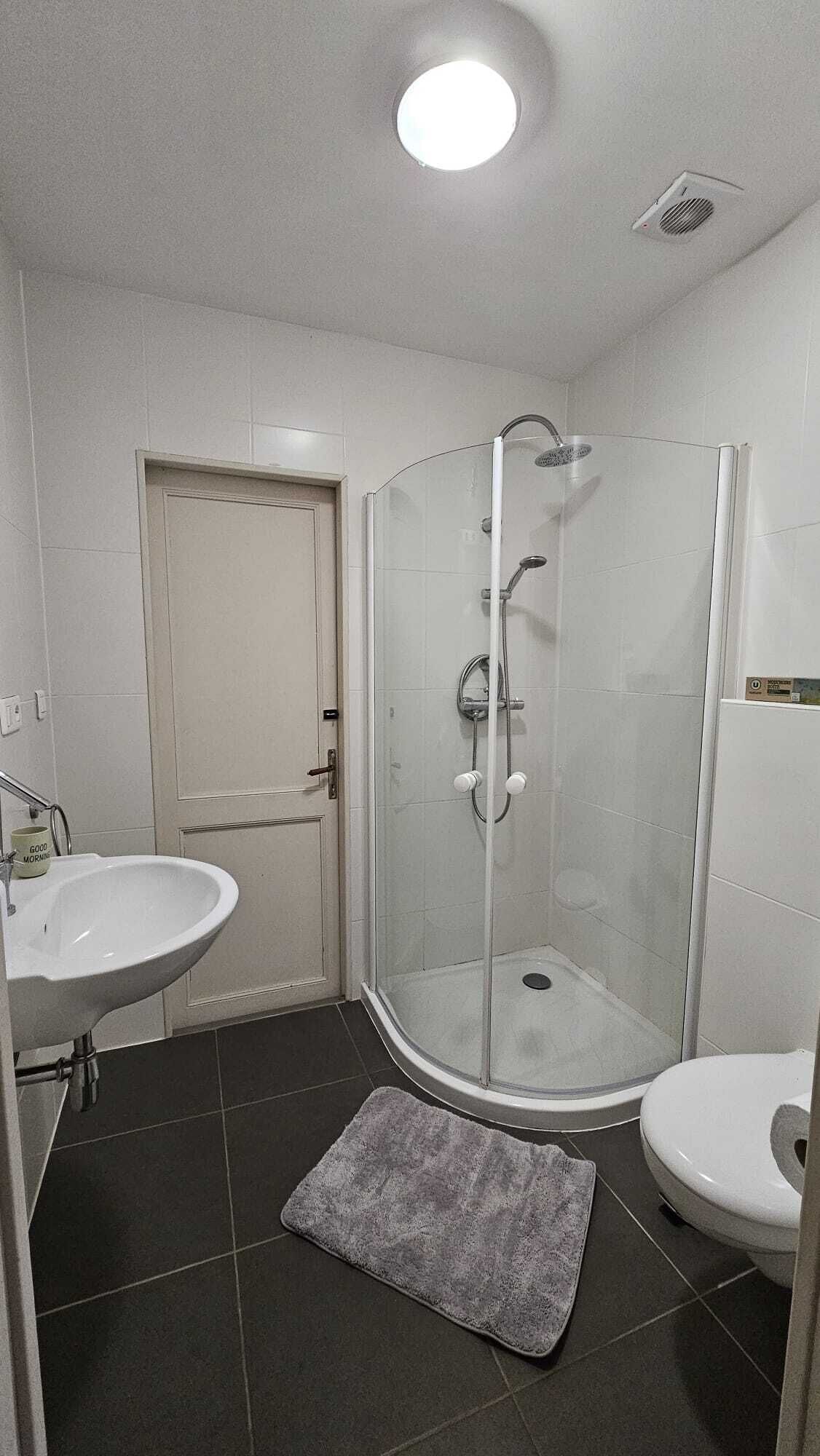 Un baño con ducha de vidrio, lavamanos y retrete.