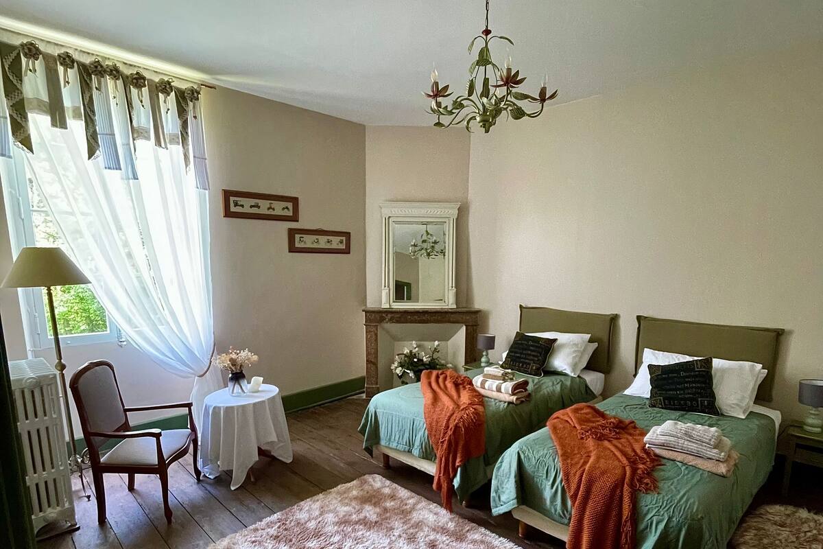 Une chambre avec deux lits, une chaise, une table et un miroir.