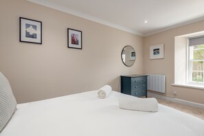 A bedroom with a bed, a dresser, a mirror, and framed pictures on the wall. - Jura Cottage | Peat Inn (Peat Inn)