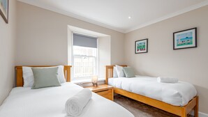 A bedroom with two single beds, a window with a view, and two framed pictures on the wall. - Jura Cottage | Peat Inn (Peat Inn)
